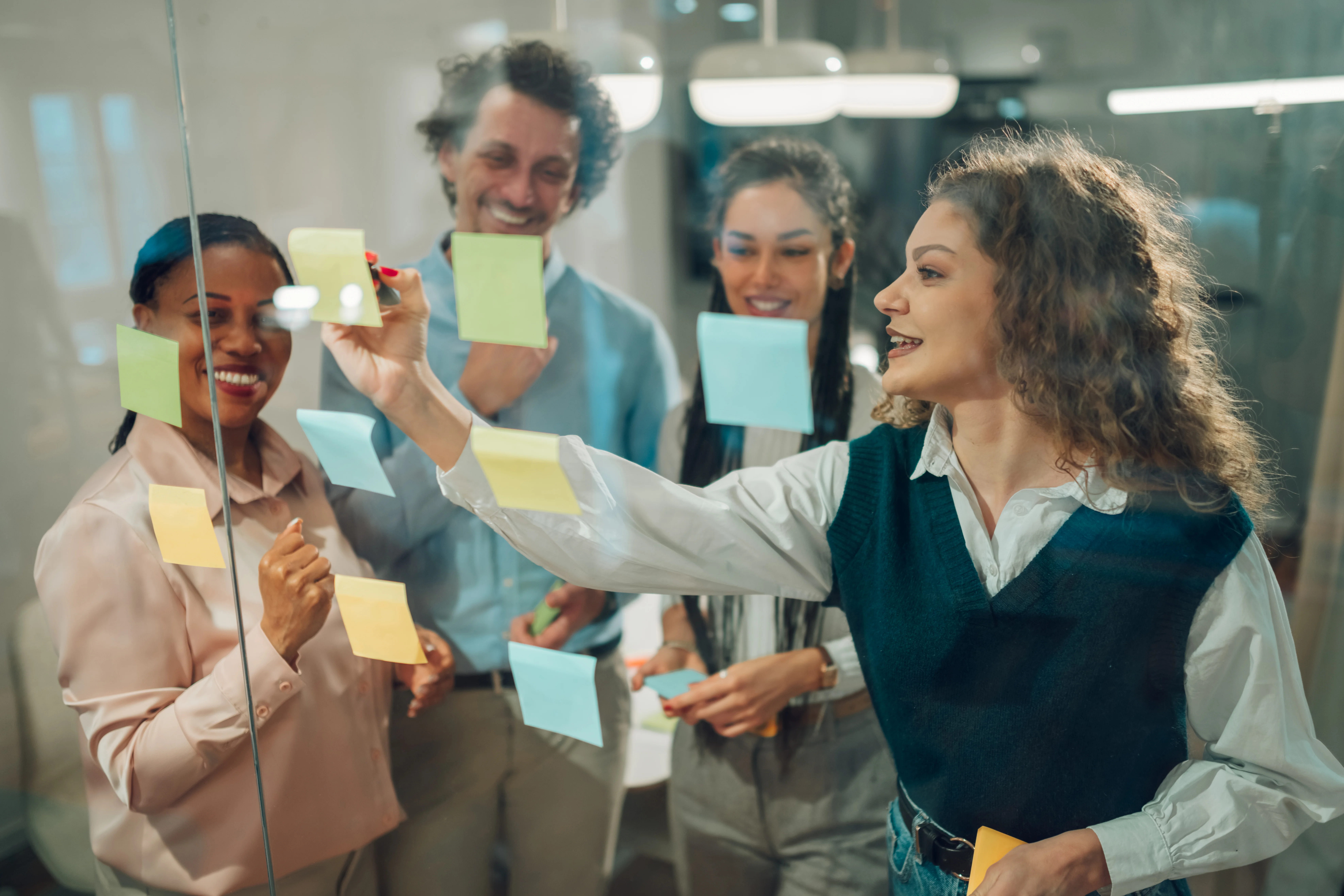 Businesspeople planning strategy using adhesive notes on glass wall in office