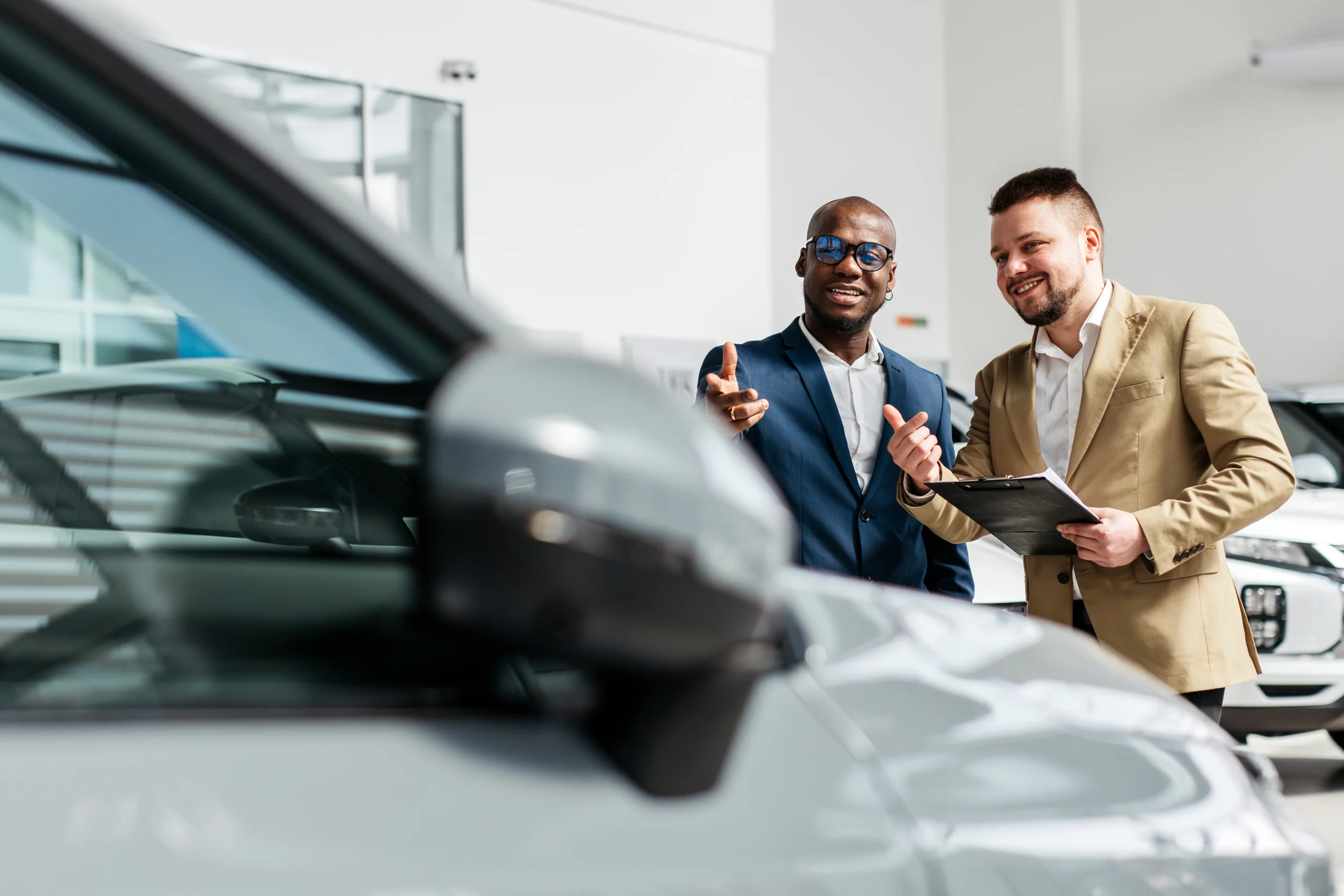 A car dealer in a modern car dealership advises an African-American customer on buying or leasing a new car. The concept of an expensive purchase or lease of a modern car.
