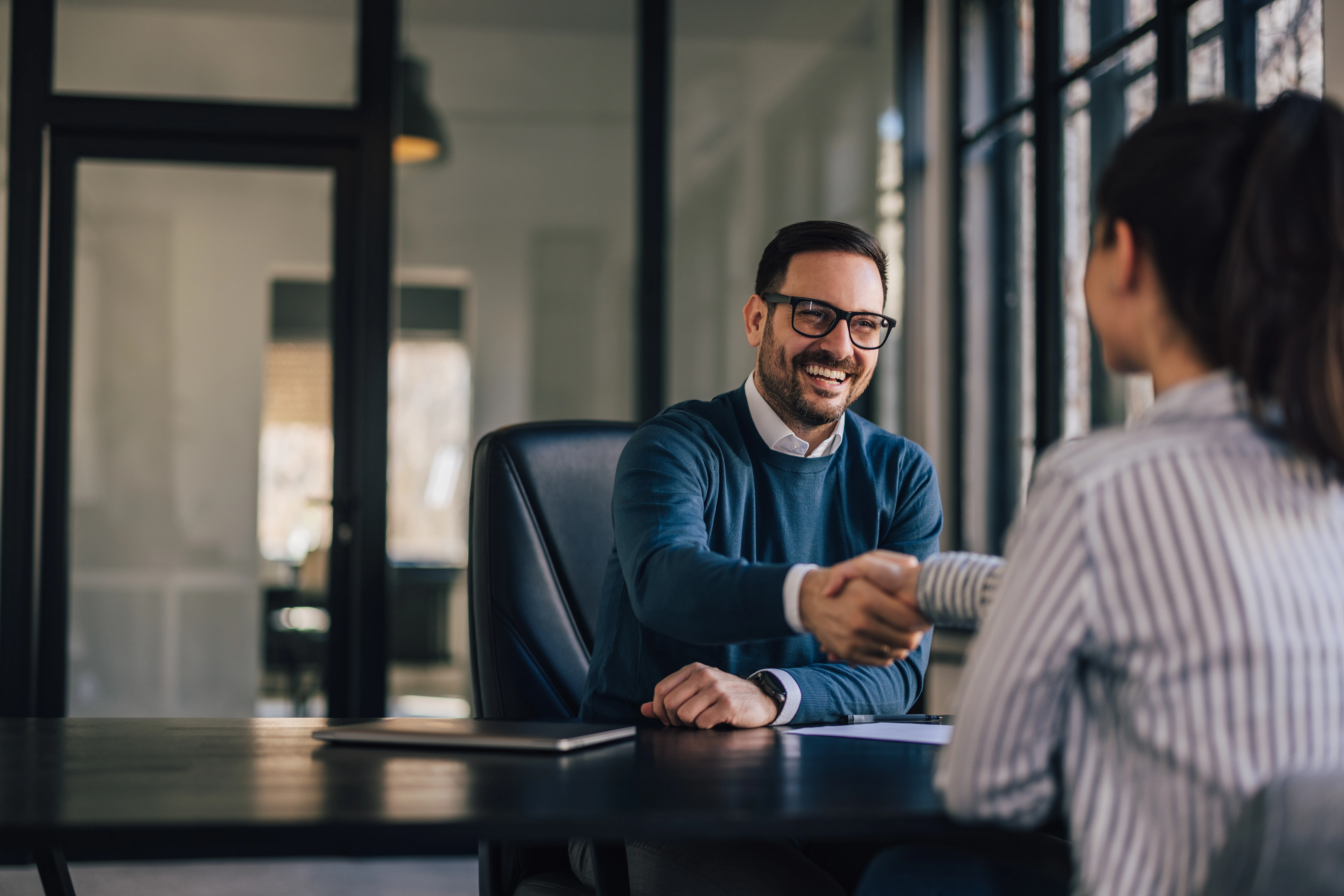 Happy businessman, shaking hands with the newly employed person.