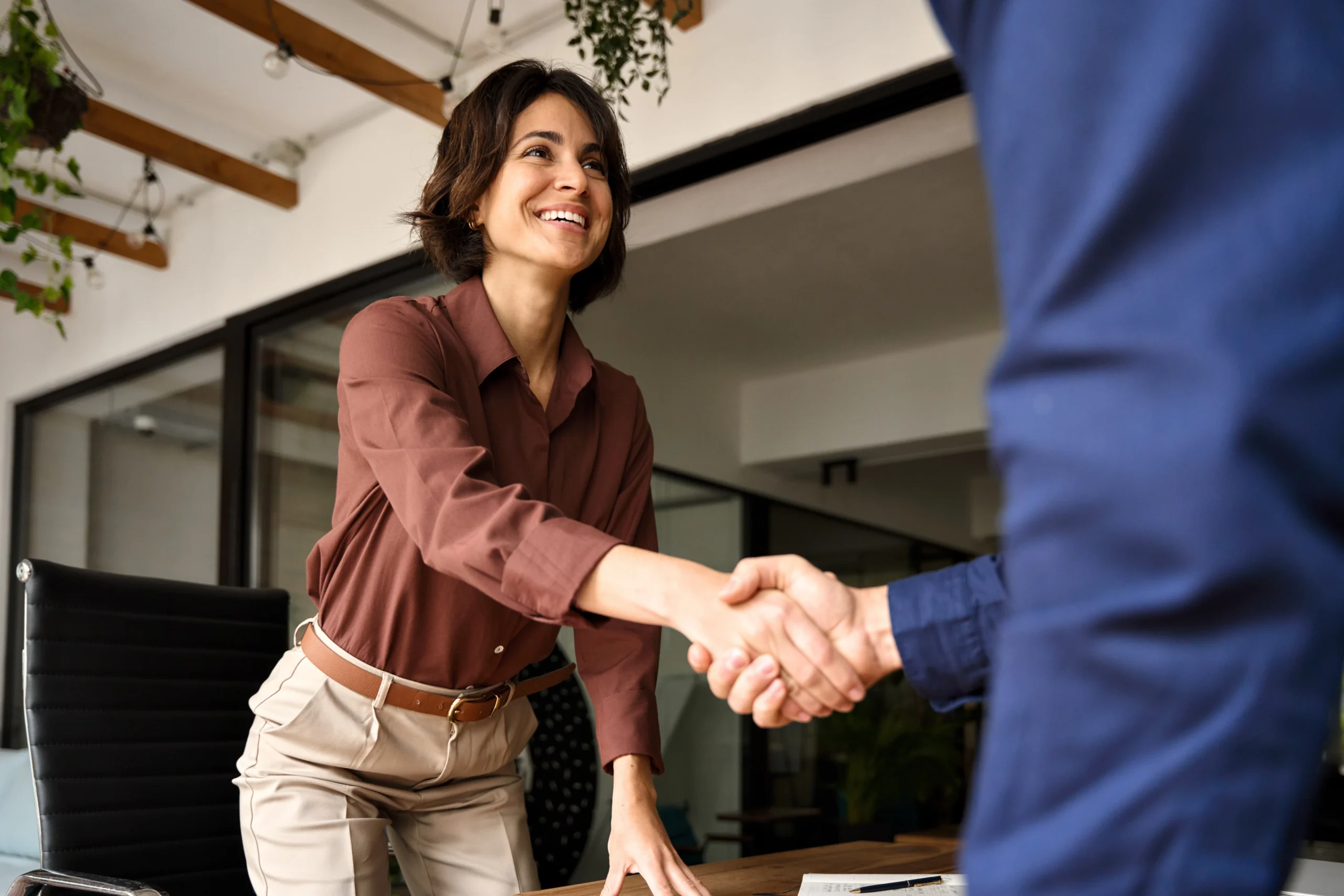 Handshake of happy young business woman and business man at office meeting. Female hr bank manager, financial advisor handshaking recruit, greeting client. Hiring at job interview, partnership concept